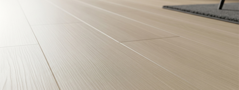 A close-up, low-angle shot of light-colored wooden floorboards, highlighting their natural grain and subtle variations. The planks are uniformly laid, creating a clean and modern aesthetic. The image captures the texture and finish of the flooring material, suggesting quality and durability.